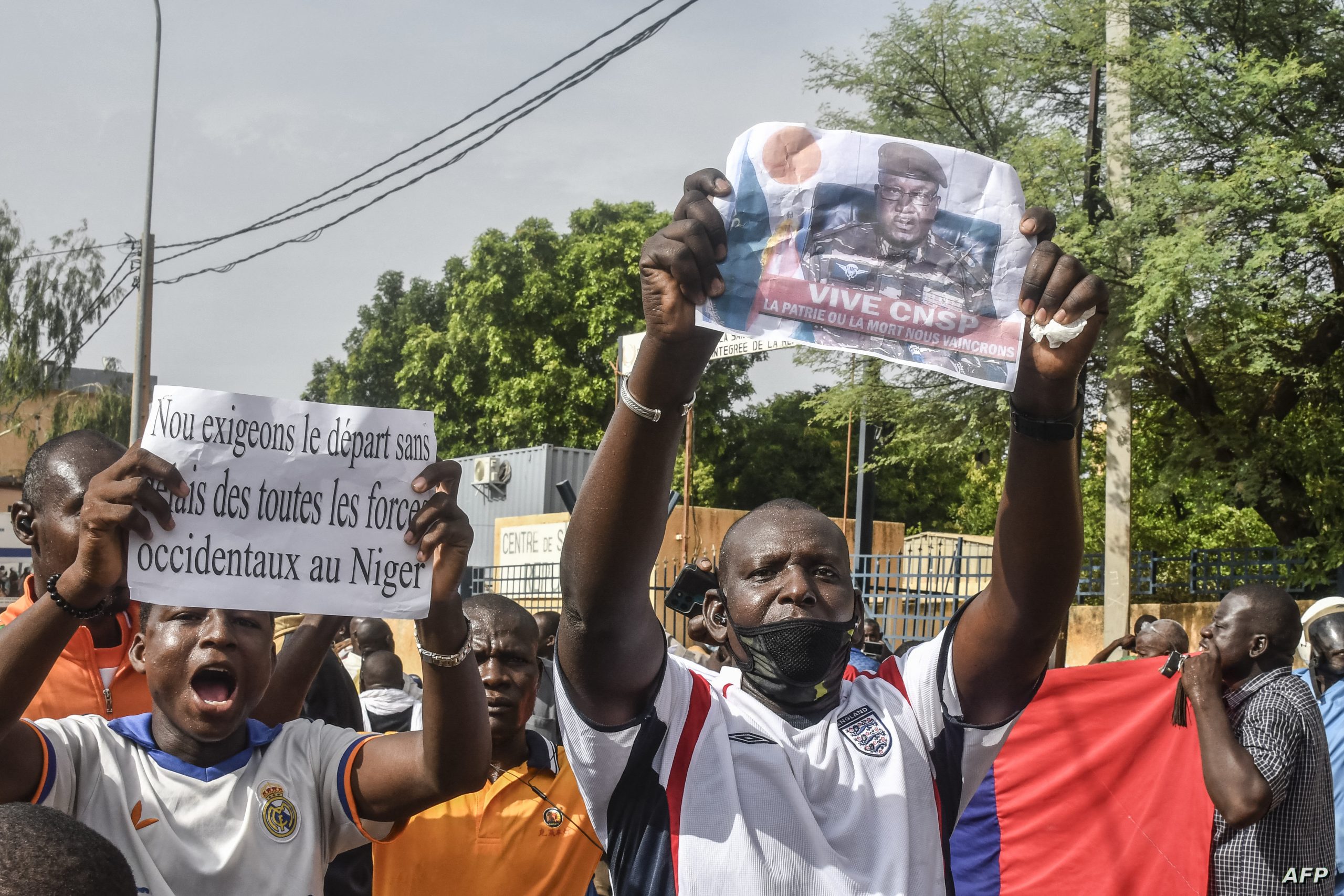 A supporter holds a picture of Niger General Abdourahamane Tiani, the chief of the powerful presidential guard, as with others rally in support of Niger's junta in Niamey on July 30, 2023. Niger's junta on Sunday said ECOWAS could stage an imminent military intervention in the capital Niamey as the regional body meets for an "extraordinary summit" on the coup-hit country, with sanctions a possibility. The country's elected president Mohamed Bazoum has been held by the military for four days, and General Abdourahamane Tiani, the chief of the powerful presidential guard, has declared himself leader. (Photo by AFP)
